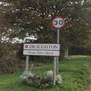 Sign of Draughton entrance and a caution to Please Drive Slowly